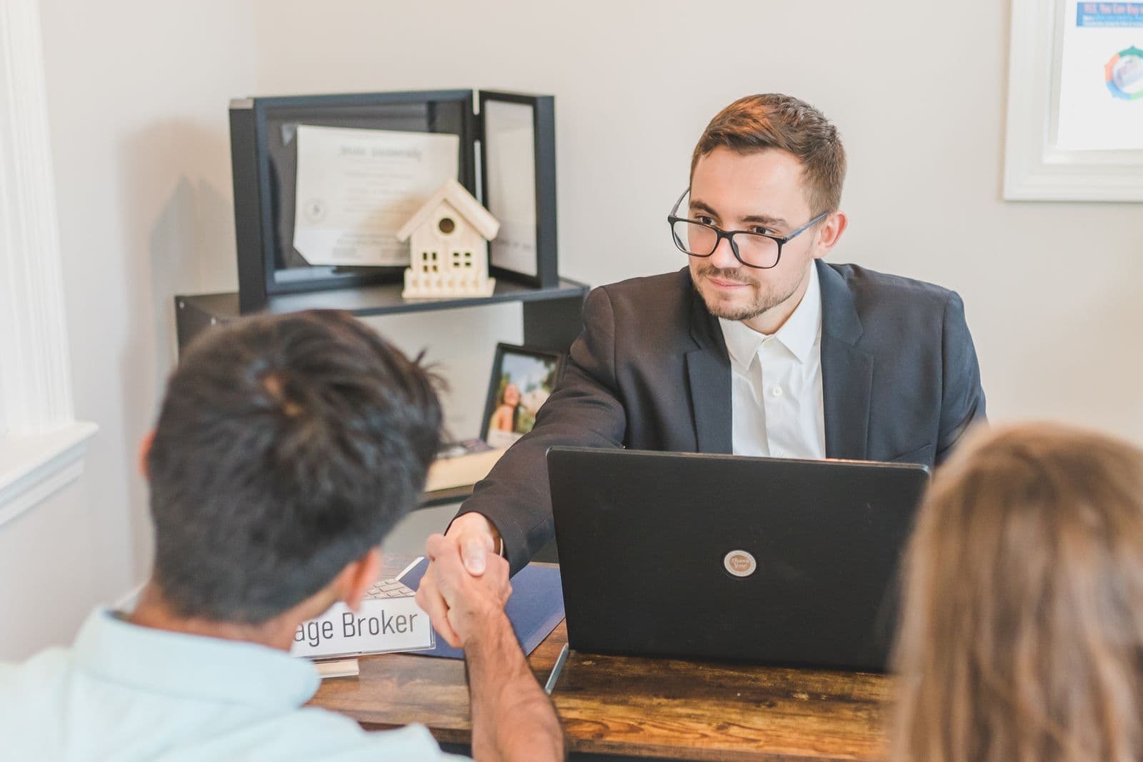 A broker meeting with clients and shaking hands across a desk