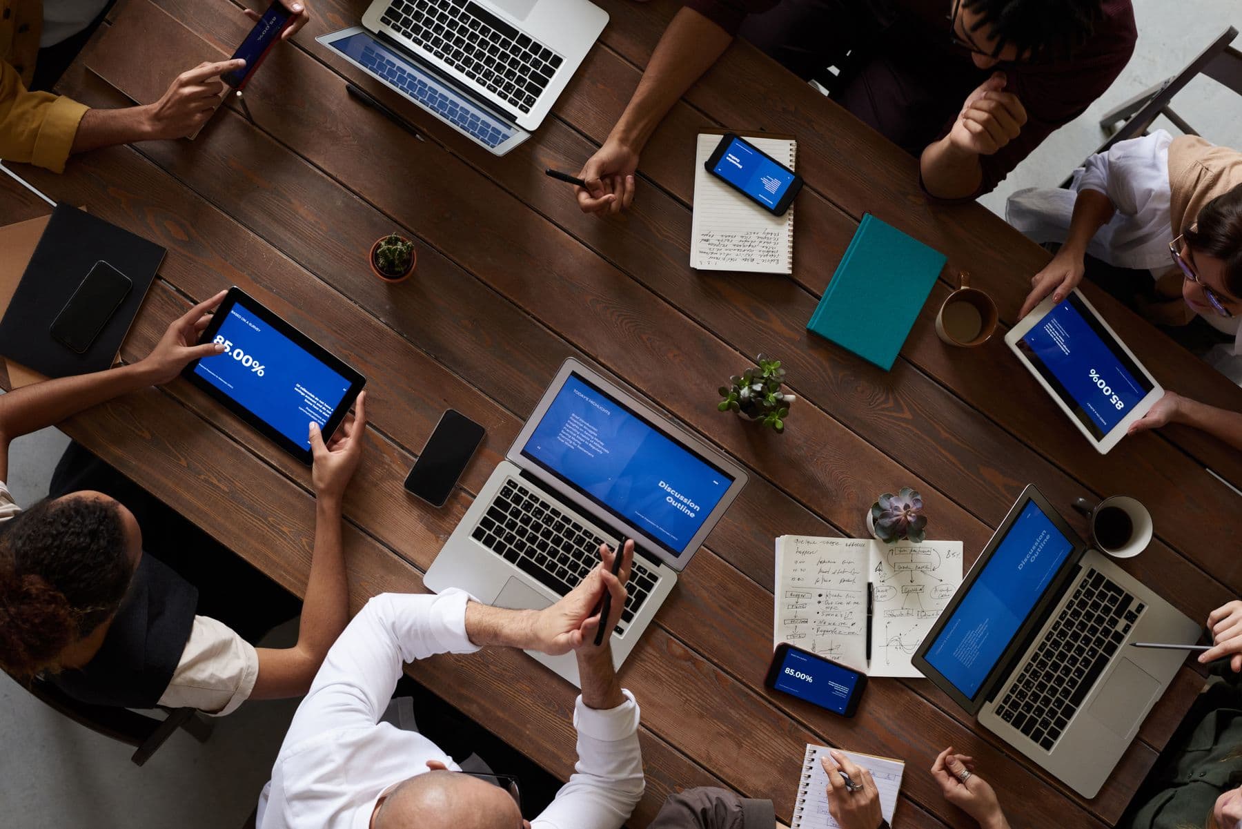 A team collaborating around a table with laptops and notes