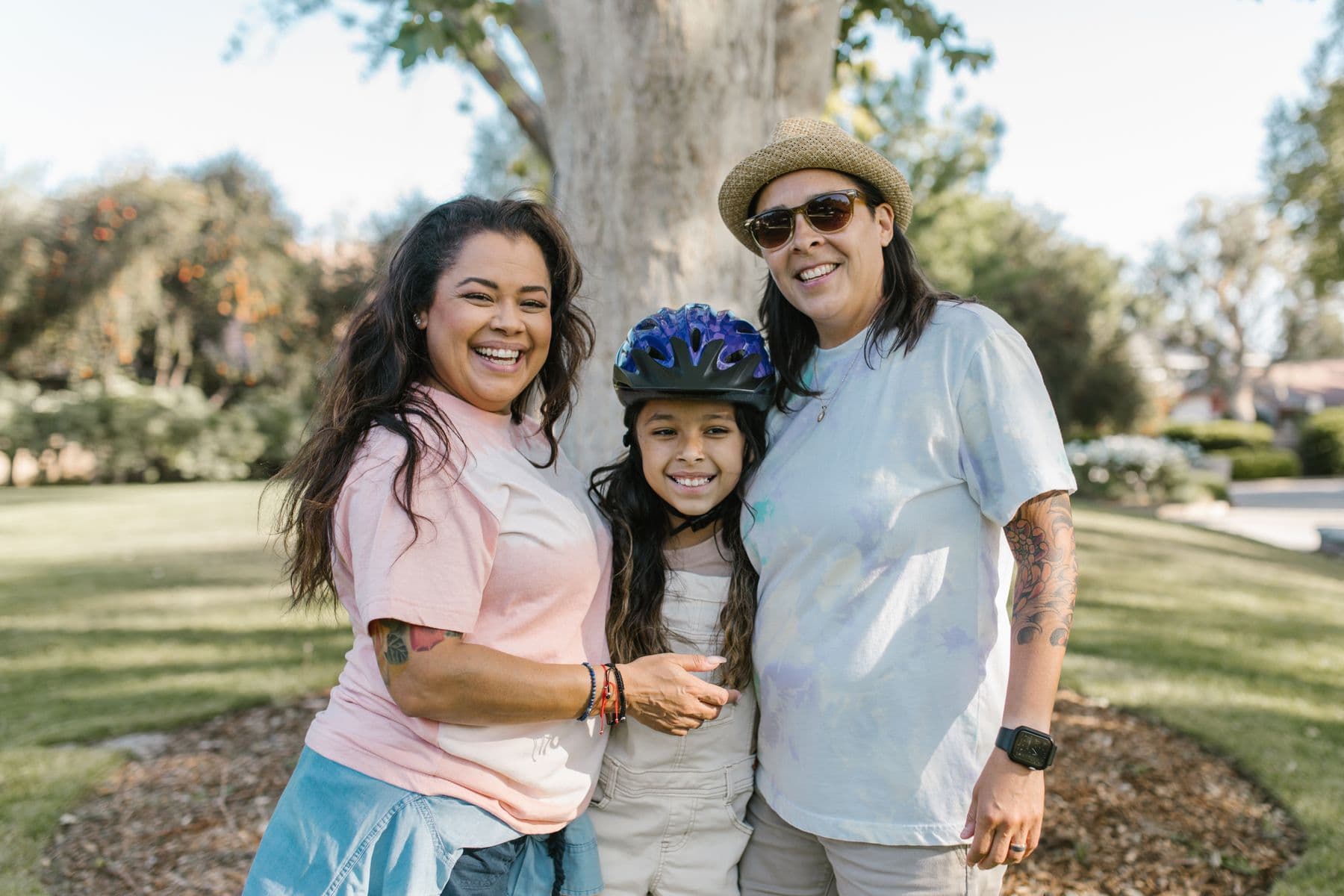 Two parents and their child smiling together outdoors